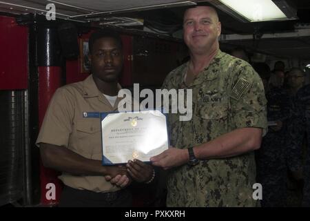 SASEBO, Japan (7. Juni 2017) Kulinarische Specialist 3. Klasse Christopher Tucker, von Dallas, der Avenger zugeordnet - Klasse Mine Countermeasure Schiff USS Warrior (MCM 10), erhält eine Navy und Marine Corps Commendation Medal von Kapitän Jim Miller, Commodore, Mine Gegenmaßnahmen Squadron 7, für schnelle Aktionen jemanden vom Ertrinken auf Commander, Flotte Aktivitäten Sasebo im späten Mai speichern. Tucker haben gemeinsam mit anderen Servicemember von kulinarischen Specialist 3. Klasse Michael Hahnrauch, von Red Hook, New York, zugeordnet zu den USS Chief (MCM 14) Beihilfen zu rendern. "Immer wenn Sie jemand sehen, benötigen Sie Stockfoto