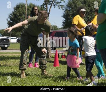 Cpl. Connor Kreuz, Transport noncommissioned Officer Leiter, G-6, US Marine Corps Forces Command, Trainer Camp Allen Schüler der Grundstufe, wie Sie Rennen in einem 50-yard Dash während der Schulen Field Day Event, am Lager Allen Volksschule, Norfolk, Virginia Marines zugeordnet MARFORCOM freiwillig den Lehrkörper und die Studierenden in den Veranstaltungen und Aktivitäten während der jährlichen Veranstaltung der Schule zu unterstützen. Stockfoto