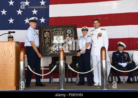 Coast Guard Master Chief Petty Officer Daniel Kelly und Lt.Cmdr. Ally M. Thompson vorhanden Kapitän Richard Craig mit Schatten, während seiner Pensionierung Zeremonie an der Coast Guard Air Station Elizabeth City, North Carolina, Juni 09, 2017. Craig in den Ruhestand nach fast 27 Jahren in der Küstenwache und drehte das Kommando der Air Station Elizabeth City während der Zeremonie. Die US-amerikanischen Küstenwache Stockfoto