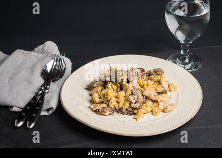 Pasta mit gegrillten Pilzen und Huhn auf dem dunklen Holz Hintergrund Stockfoto
