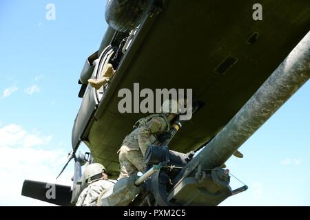 New York Army National Guard Soldaten vom 1. Battalion, 258Th Field Artillery schließen Sie ein M119A2 howitzer zu einem UH-60 Black Hawk Hubschrauber auf Fort Drum, N.Y., 8. Juni 2017. Die Haubitze wurde zu einem Bereich, in dem es sicher als Teil des jährlichen Trainings der Einheit abgefeuert werden könnten transportiert. Stockfoto