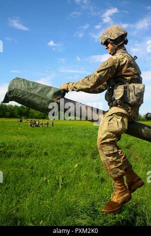 New York Army National Guard Pfc. William Nolan eine Kanone crewmember zu Alpha Batterie, 1st Battalion, 258Th Artillerie Regiment, 27 Infantry Brigade Combat Team zugeordnet ist, wird in eine 105-mm-Haubitze M119A2 für Schleuder- Operationen während eines Air Assault Artillerie raid am Fort Drum, N.Y. am 9. Juni 2017. Nach dem Einlegen der simulierten feindliche Ziele, die Waffe Besatzungen mussten schnell die Waffen nach unten nehmen und sie für die Extraktion prep. Stockfoto