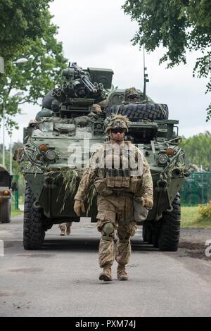 Eine Battle Group Polen US-Soldat Escorts ein M1126 Stryker vor der Fahrt beim Start der Bereich Ausbildung übung Teil von Sabre Streik 2017 Die taktische Montagebereich an Bemowo Piskie, Bemowo Piskie, Polen, 13. Juni 2017. Sabre Streik 17 ist eine US-Army Europe-geführten Multinationalen Kräfte kombiniert jährlich durchgeführten Studie des NATO-Bündnisses im gesamten Ostseeraum und Polen zu verbessern. Die diesjährige Übung beinhaltet integrierte und synchronisierte Abschreckung-orientierte Ausbildung für die Interoperabilität und die Bereitschaft der 20 teilnehmenden Nationen Streitkräfte zu verbessern. Stockfoto