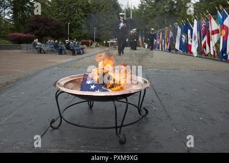 BANGOR, Washington (14. Juni 2017) Chief Rakete Techniker Adrian Roe, von König William, Virginia, Trident Training Service Bangor zugeordnet, Spaziergänge die Überreste eines US-Flagge zu einem Brand während einer Flagge in den Ruhestand Zeremonie am Marinestützpunkt Kitsap - Bangor. Wenn eine US-Flagge abgenutzt, zerrissen, blasse oder stark verschmutzt, die Flagge mit der Würde und Achtung, die es in den Ruhestand versetzt. Die traditionelle Methode ist die Fahne in Stücke zu schneiden, trennen die 13 Streifen von Kanton und verbrennen Sie separat in einer respektvollen Weise. Stockfoto