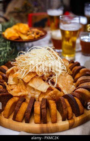 Leckere Snacks für Bier. Vorstand mit Käse, Chips von Weizen und Roggen Brot, in der Nähe von Bier Stockfoto