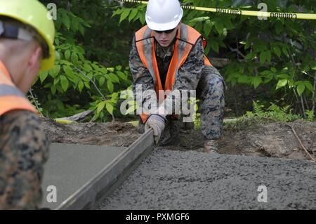 Marines aus GER CO "Charlie" 6. Techniker Bataillon 4. Marine Logistics Group, Peoria, IL glatter Beton für die neue Sitzbank Denkmal zu Ehren eines verstorbenen Kind camp antendee im Camp William Hinds, Raymond, Maine am 14. Juni 2017. Mitglieder aus den 122 Fighter Wing Bauingenieurwesen Squadron, Fort Wayne, IN, Air Force Reserve Mitglieder aus der 482Nd Tiefbau Squadron, Homestead ARB, FL, Marines von der Landung Support Firma CLR-45 th Marine Logistics Group, Savannah, GA, und Marines aus GER CO "Charlie" 6. Techniker Bataillon 4. Marine Logistics Group, Peoria, IL als Stockfoto
