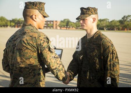 Us Marine Corps Staff Sgt. Devon Luevano, Senior drill instructor von Platoon 2044, Golf Company, 2 Recruit Training Bataillon, Hände die begehrten Adler, Globus und Anker Emblem zu US Marine Corps Pfc. Sean G. McCool während einer Zeremonie an der Iwo Jima flag Statue anheben 3. Juni 2017, auf Parris Island, S.C. Die Zeremonie, nach der letzten Wanderung der Ausbildung rekrutieren, markiert das Ende der Transformation von in United States Marine rekrutieren. Golf Company graduierte Juni 9, 2017. Heute, rund 19.000 Rekruten kommen auf Parris Island jährlich für die Chance, United States Marines werden Stockfoto