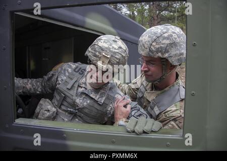 Us-Armee Kaplan 1. Lt. Justin Warfel (rechts), um die 129 mobilen öffentlichen Angelegenheiten Loslösung, South Dakota Army National Guard angefügte Spc unterstützt. Shae Weber aus einem Humvee während der Zähler Improvised Explosive Device Lane als Teil des Goldenen Coyote Übung an der Basis Custer, S.D., 18. Juni 2017. Die goldenen Coyote Übung ist eine dreiphasige, Szenario-driven Übung in den Black Hills von South Dakota und Wyoming, mit dem Kommandanten auf der Mission wesentliche Anforderungen der Aufgabe, Krieger Aufgaben und Übungen zu konzentrieren. Stockfoto