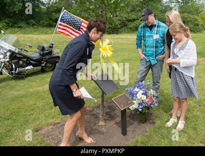 Shelly Raynes stellt eine Tafel vor einem Baum zu ihrem verstorbenen Ehemann gewidmet, pensionierter Tech. Sgt. John raynes, während ein Memorial Park Einweihung an hanscom Air Force Base, Mass., 16. Juni, während John Jr., Ashley und Hannah Gnade auf. Raynes arbeitete für Sicherheitskräfte, Öffentliche Angelegenheiten und Tiefbau während seines Besitzes an hanscom. Auch während der Dauer der Veranstaltung geehrt wurde Dana E. Kirane und Dennis "Dennie "Guthrie. Stockfoto