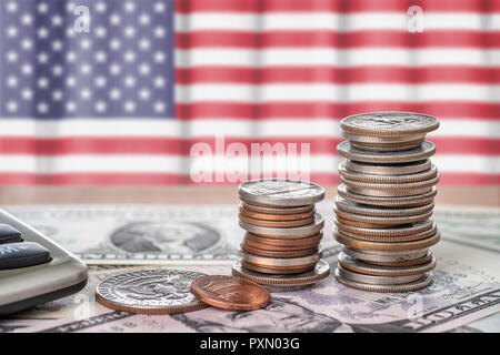 Banknoten und Münzen vor der Flagge der USA Stockfoto