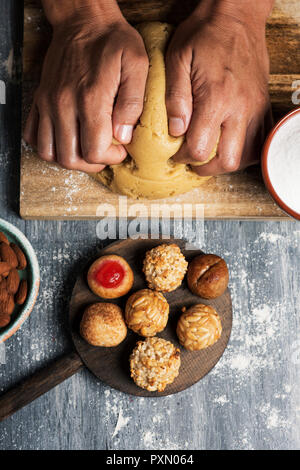 Hohe Betrachtungswinkel und einer jungen kaukasischen Mann Vorbereitung einige Panellets süße Lebensmittel in der Regel in Allerheiligen in Katalonien, Spanien gegessen Stockfoto