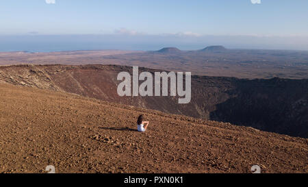 Mädchen sitzt auf einem Vulkan, Fuerteventura Stockfoto