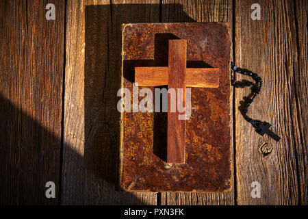 Christliche Kreuz auf Holz, Bibel und Rosenkranz über Holz- vintage Hintergrund Stockfoto