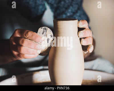 Erstellen von Steingut und traditionelle Töpferei Konzept. Die erfahrenen männlichen potter Hände schöne Ton Produkt-Vase - mit professionellen Werkzeug Stockfoto