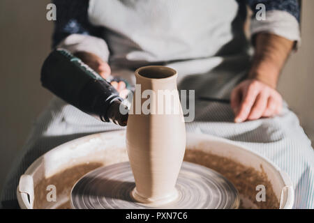 Erfahrene männliche Potter bläst trockene Ton, er schöne Ton Produkt - Kanne - mit Hilfe professioneller Tools. Getönten filmische, Handwerk factory Authen. Stockfoto