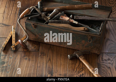 Antike Werkzeuge und grunge Toolbox auf dunklem Holz Oberfläche Stockfoto