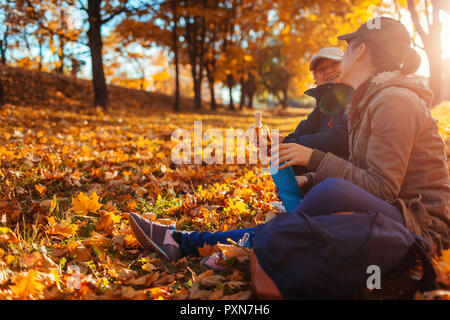 Paar Touristen mit Rucksäcken auf der Suche nach der rechten Weise mit Navigator auf dem Telefon im Herbst Wald. Frauen Rest in Stockfoto