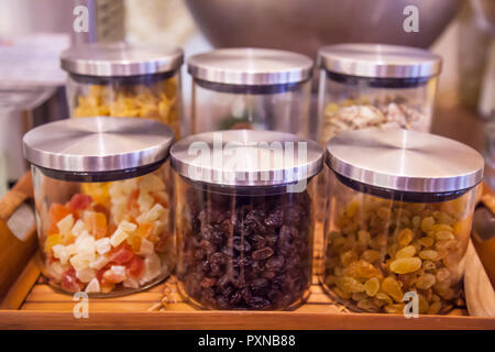 Süße bunte Glas Tassen, Gläser oder Flaschen in Holz- fach in Küche oder Speisekammer für toppings (jelly, Korinthen, Sultaninen, Rosinen, Trauben, ce Stockfoto