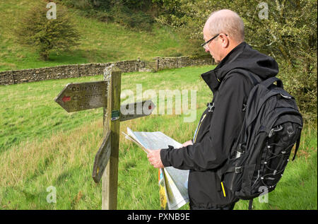 Mann Person Wanderer Blick auf eine Karte auf dem Dales Way Wanderweg Weg Spaziergang im Spätsommer in der Nähe von Windermere Cumbria England Großbritannien Großbritannien Stockfoto