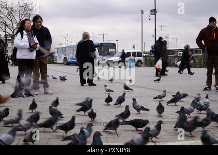 Istanbul, Türkei - 19 Februar 2018: Zwei asiatische Touristen sind unter Foto der Tauben am Eminönü Square. Auch viele Türken sind vorbei. Stockfoto