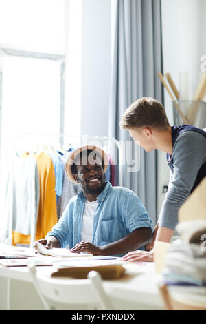 Zwei lächelnde junge Designer ihre Arbeit diskutieren, gemeinsam bei der fashion Studio Stockfoto