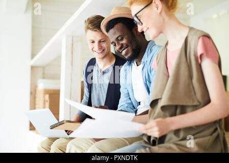 Gruppe von Jugendlichen zusammen zu sitzen, als Team mit Papieren und Vorbereitung auf Prüfungen Stockfoto