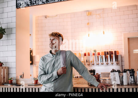 Junger Mann bei der Arbeit in seinem Start-up-Cafe, Bar, Tagträumen Stockfoto
