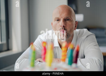 Geschäftsmann seinen Geburtstag feiern im Büro, Kerzen ausblasen Stockfoto