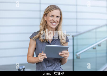 Lächelnde blonde Geschäftsfrau mit Tablet Stockfoto