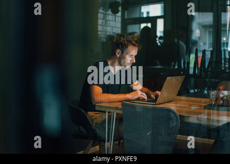 Mann sitzt im Büro, spät in seinem Start-up-Unternehmen arbeiten