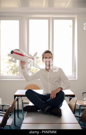 Geschäftsmann spielen mit aufblasbaren Flugzeug im Büro Stockfoto