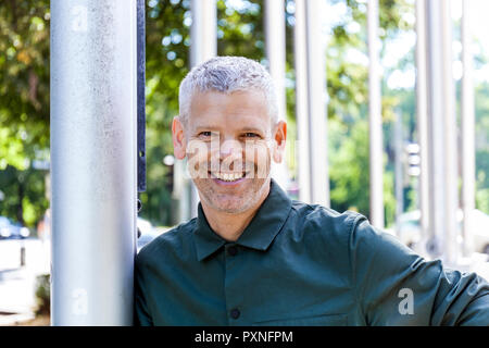 Porträt eines lächelnden reifer Mann gegen einen Pfosten gelehnt Stockfoto