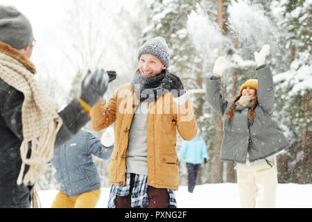 Jolly begeistert Schüler Spaß im Winter Pak in: fröhlicher Kerl in der Schal Gestik, die Hände beim Schutz von Schneebällen Stockfoto