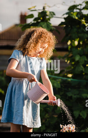 Kleines Mädchen Blumen im Garten gießen Stockfoto