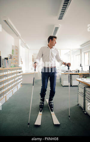 Geschäftsmann Skifahren im Büro Stockfoto