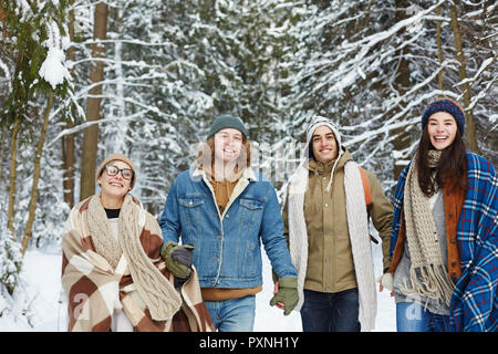 Taille bis Porträt des modernen jungen Menschen zu Fuß in Richtung Kamera im Winter Resort und glücklich lachend Stockfoto