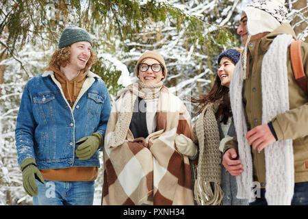 Portrait von vier glückliche junge Menschen im Winter Resort im verschneiten Wald posing und freundlich lächelnd Stockfoto