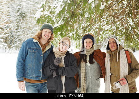 Taille bis Porträt der Gruppe der glückliche junge Menschen im Winter Resort posing stehen unter Tannenbaum in der schönen verschneiten Wald Stockfoto