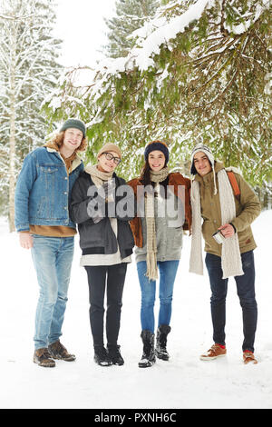 In voller Länge Porträt der Gruppe der glückliche junge Menschen im Winter Resort posing stehen unter Tannenbaum in der schönen verschneiten Wald Stockfoto