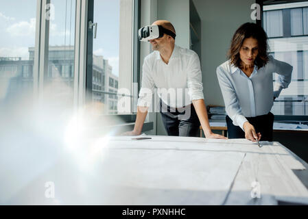 Zwei Architekten, die auf Blueprints, Mann mit VR-Brille Stockfoto