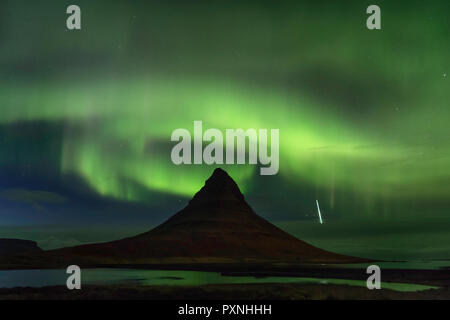 Grundarfjörður, Island - die Aurora borealis Spiralen über der Oberseite der Gipfel des Mount Kirkjufell als Shooting Star Weg durch die Atmosphäre. Stockfoto