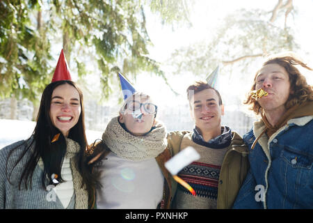 Gruppe der glückliche junge Menschen feiern Weihnachten draußen im schönen Wald, alle tragen Partei Kappen Stockfoto