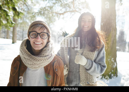Porträt von zwei modernen jungen Frauen in Richtung Kamera, während Sie zu Fuß in der schönen Winter Forest im Sonnenlicht Stockfoto