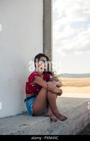 Portrait von teenage Mädchen tragen Sonnenbrillen unter den Schattierungen auf Distanz suchen Sitzen Stockfoto