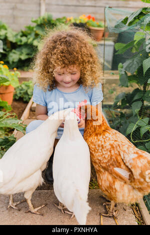 Kleines Mädchen Fütterung Hühner in Zuteilung Stockfoto