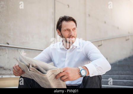 Lächeln, Geschäftsmann, sitzen auf der Treppe lesen Zeitung Stockfoto