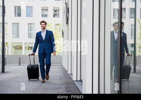 Lächelnd Geschäftsmann mit Gepäck in der Stadt in Bewegung Stockfoto