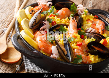 Spanische traditionelle Küche: heiße Paella mit Meeresfrüchten Shrimps, Muscheln, Fisch, und baby Kraken close-up in einer Pfanne auf dem Tisch. Horizontale Stockfoto