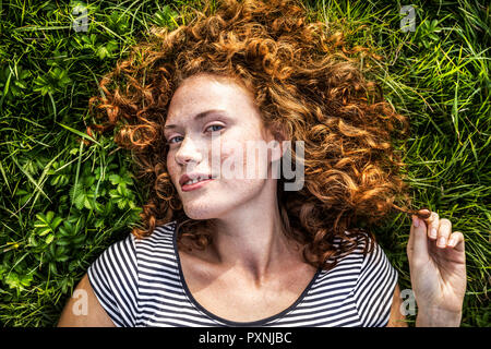 Portrait von lächelnden jungen Frau liegt auf einer Wiese Stockfoto