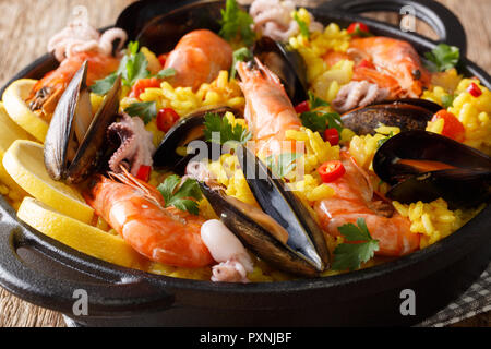 Spanische Paella essen mit Fisch und Meeresfrüchten Shrimps, Muscheln, Fische und Tintenfische close-up in einer Pfanne auf dem Tisch. horizontal, rustikalen Stil Stockfoto